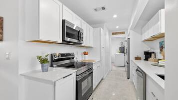 Una cocina moderna con armarios blancos, electrodomésticos de acero inoxidable y una isla central.