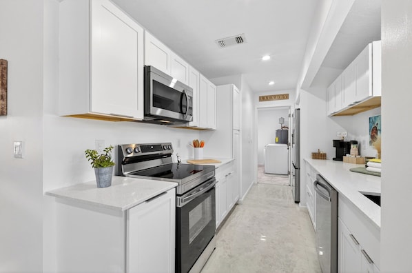 A modern kitchen with white cabinetry, stainless steel appliances, and a central island.