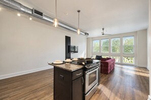 A modern kitchen with a central island, stainless steel appliances, and a large window providing natural light. - Design District 1BR | Reserved Parking | Sleeps 4 (Dallas)