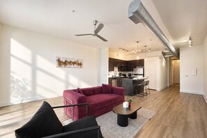 Ein modernes Wohnzimmer mit einem roten Sofa, einem schwarzen Sessel, einem Couchtisch und einem Deckenventilator.