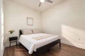 A bedroom with a bed, a nightstand, a framed picture, and a ceiling fan. - Design District 1BR | Reserved Parking | Sleeps 4 (Dallas)