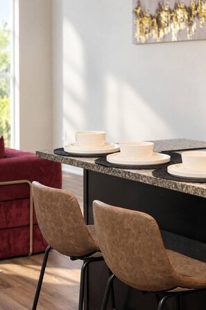 Eine moderne Küche mit einer Granit Arbeitsplatte, weißen Schüsseln und einem roten Sofa.