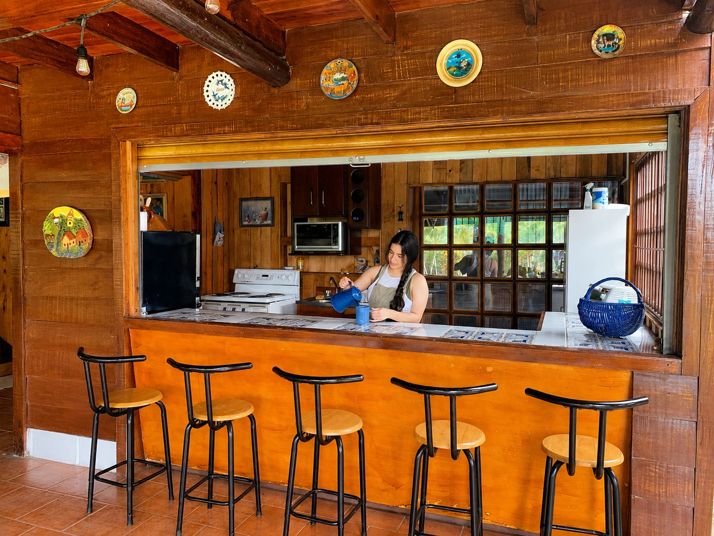 A bar area with a counter, stools, and a person behind the bar.