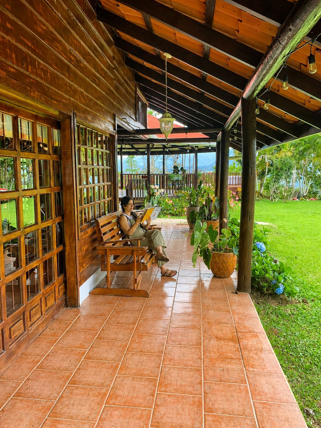 A covered outdoor seating area with wooden benches and potted plants.