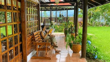 A covered outdoor seating area with wooden benches and potted plants.