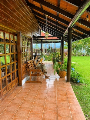 A covered outdoor seating area with wooden benches and potted plants.