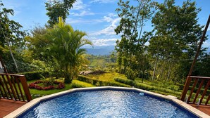 Una piscina con vista su un paesaggio rigoglioso, circondata da un pontile in legno e luci decorative.