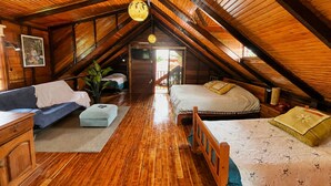 Una camera da letto mansardata accogliente con travi in legno, un divano, un letto e una televisione.