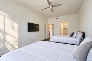 Une chambre avec deux lits, un ventilateur de plafond et un téléviseur fixé au mur.
