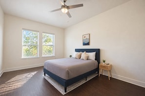 A bedroom with a bed, a ceiling fan, a nightstand, and a window. - Design District 2BR/2BA | Sleeps 6 | Parking (Dallas)