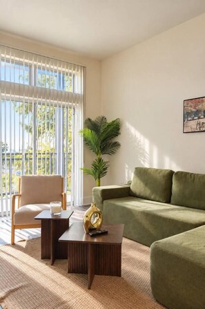 A living room with a sofa, a chair, a coffee table, and a plant. - Design District 2BR/2BA | Sleeps 6 | Parking (Dallas)