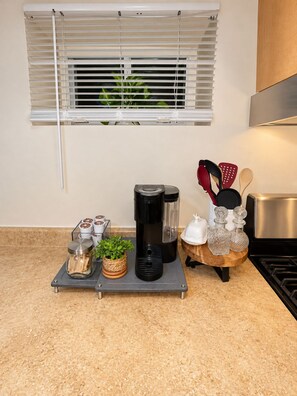 A kitchen counter with a coffee maker, a spice rack, and a window with blinds. - Cozy 1-bedroom apartment in fabulous Queens with AC (Queens)