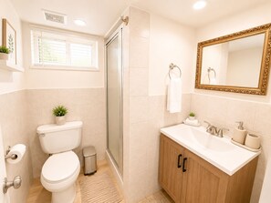 Ein Badezimmer mit Toilette, Waschbecken, Spiegel und Dusche.