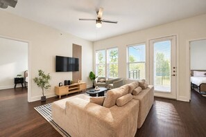 Ein modernes Wohnzimmer mit einer großen Couch, einem Fernseher und einem Deckenventilator.
