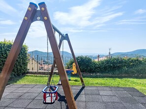 Um balanço em um parque, com vista para colinas e edifícios ao longe.