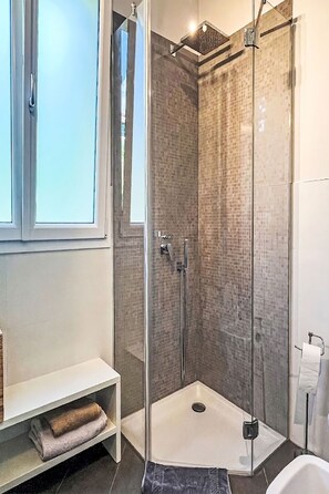 Et stilfuldt badeværelse med brusekabine i glas, et hvidt håndvask og toilet.