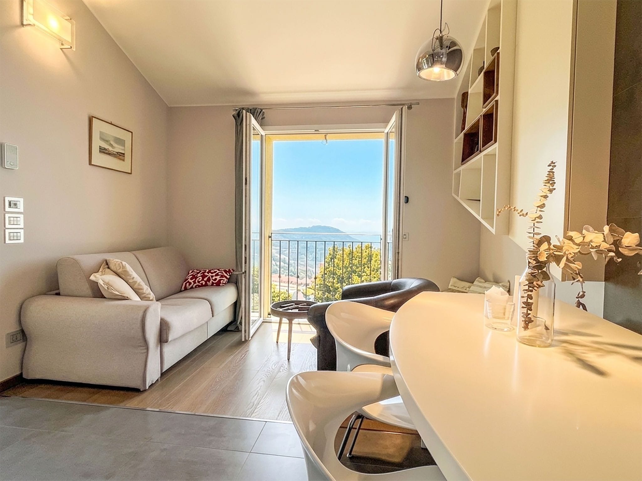 Un salon moderne avec un canapé, un coin repas avec une table et une vue sur une montagne, visible à travers une grande fenêtre.