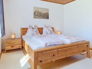 Ein Schlafzimmer mit einem hölzernen Bett, zwei Nachttischen, einer Wandlampe und einem gerahmten Bild.