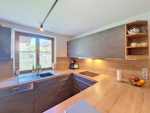 Eine moderne Küche mit integriertem Spülbecken, Holzschränken und einem Fenster mit Blick auf Grünflächen.