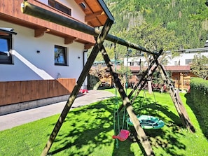 A wooden swing set in a well-maintained garden with a building in the background. - Edelweiß by Interhome (Mayrhofen)