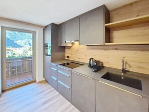 A modern kitchen with a large window, wooden countertop, and built-in appliances. - Edelweiß by Interhome (Mayrhofen)