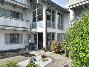 A multi-story building with a central staircase, balconies, and a garden area with potted plants and flowers. - Brünnsteinzauber by Interhome (Oberaudorf)