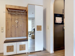 A modern kitchen with a built-in oven, a refrigerator, and a wooden cabinet with a bench. - Brünnsteinzauber by Interhome (Oberaudorf)