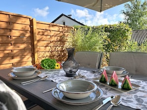 An outdoor dining area with a table set for four, including plates, bowls, and cutlery. - Brünnsteinzauber by Interhome (Oberaudorf)