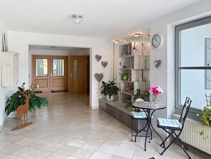 A modern interior with a tiled floor, a wooden door, a glass wall, a round table with chairs, and decorative heart-shaped items on the wall. - Brünnsteinzauber by Interhome (Oberaudorf)
