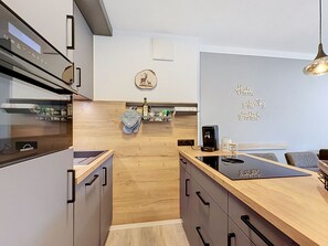 A modern kitchen with wooden cabinets, a built-in oven, and a coffee machine. - Brünnsteinzauber by Interhome (Oberaudorf)
