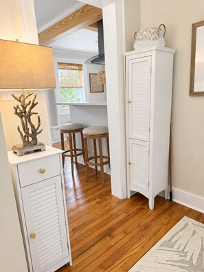 A hallway with a white cabinet, a lamp, and a wooden floor. - Cozy 2-bedroom house in beautiful Morehead City (Morehead City)