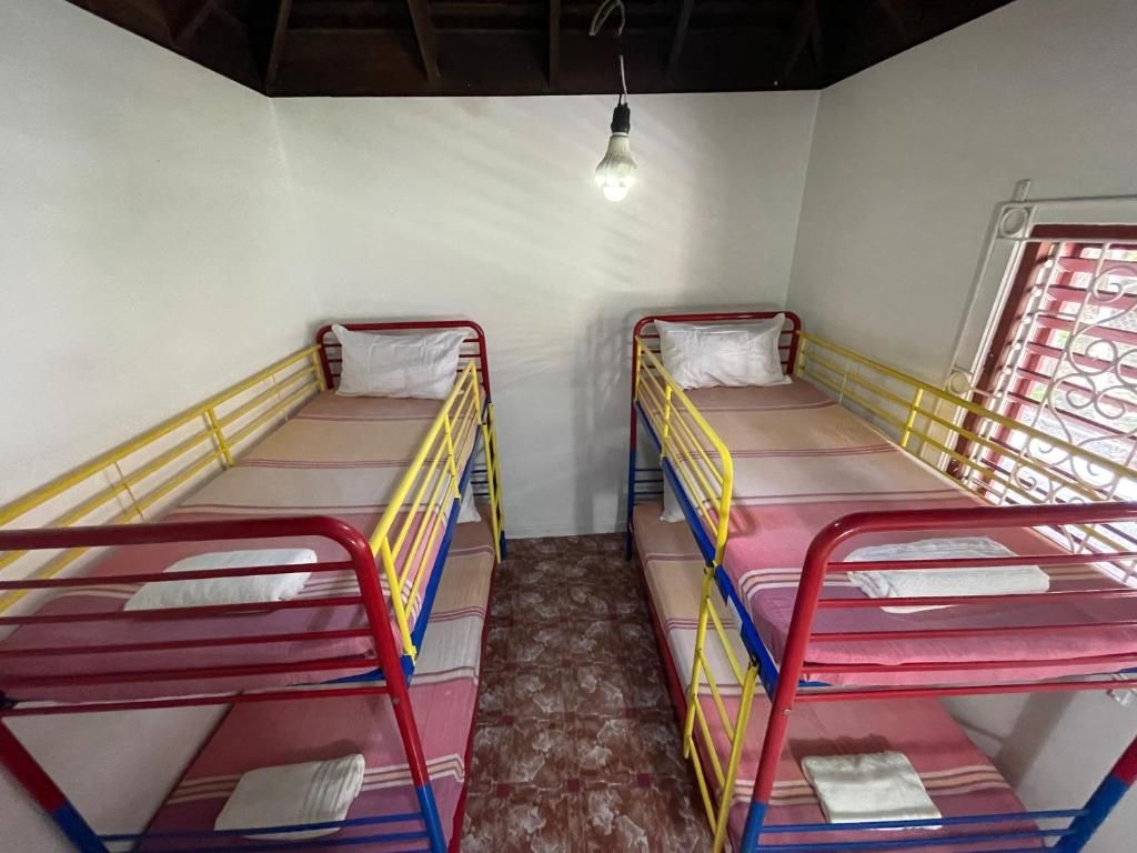 A room with two bunk beds, each with a mattress and pillow, and a single light fixture on the ceiling.