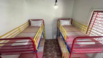 A room with two bunk beds, each with a mattress and pillow, and a single light fixture on the ceiling.
