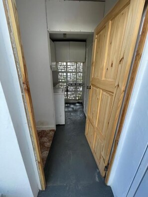 A narrow hallway with a wooden door on the right and a white door on the left.