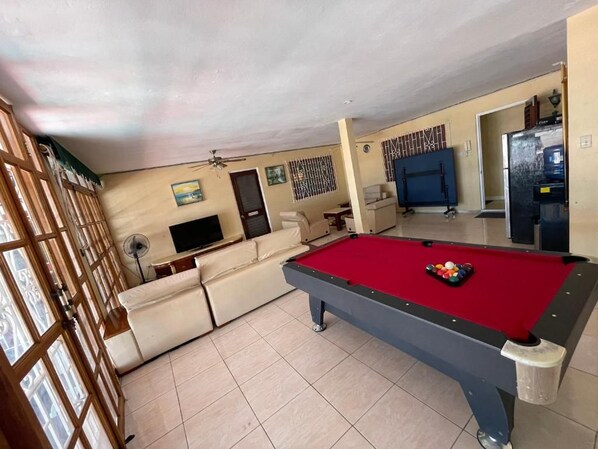 A pool table in a room with a sofa and a television.