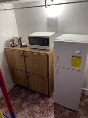 A kitchenette with a microwave, toaster, and refrigerator.