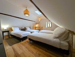 A room with two beds, a small table, a lamp, and a wooden floor.