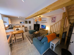 Un espai habitable reduït amb petita cuina, sofà, taula de dinar i escala.