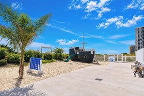 A beachside area with a lifeboat, a concrete walkway, and a sign for beach restrooms. - Carousel 606 (Ocean City)