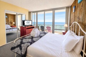A hotel room with a bed, a television, a view of the ocean, and a balcony with chairs. - Carousel 606 (Ocean City)