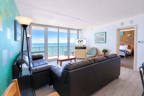 Ein modernes Wohnzimmer mit einem großen Fenster, einer Couch, einem Sessel und einem Tisch. Ein Schild für Ocean City Vacation Homes.