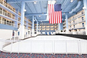 A multi-level hotel interior with balconies, a central atrium, and an American flag. - Carousel 606 (Ocean City)