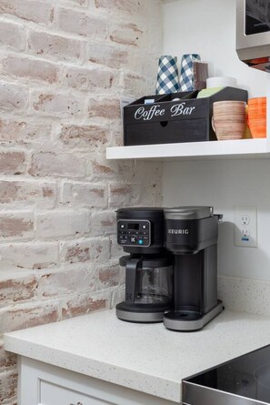 A coffee maker on a countertop with a coffee bar box and cups. - Historic 1BR Bungalow | Roosevelt Row & Downtown (Phoenix)