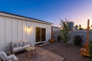 A patio with a sofa, a small table, and a wooden chair. - Historic 1BR Bungalow | Roosevelt Row & Downtown (Phoenix)