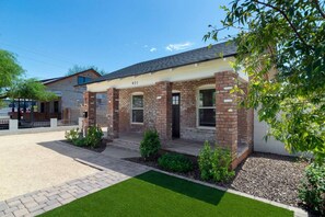A two-story house with a brick facade, a front porch, and a well-maintained lawn. - Historic 1BR Bungalow | Roosevelt Row & Downtown (Phoenix)