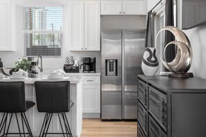A modern kitchen with white cabinets, stainless steel appliances, and a coffee bar. - Modern 2BR Casita | Roosevelt Row & Downtown (Phoenix)