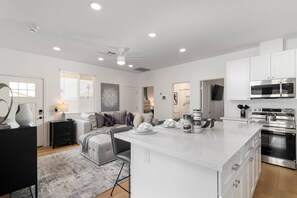 A modern kitchen with white cabinetry, a central island, and stainless steel appliances. - Modern 2BR Casita | Roosevelt Row & Downtown (Phoenix)