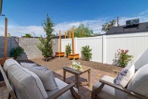 A backyard patio with outdoor furniture, a small table, and a white fence. - Modern 2BR Casita | Roosevelt Row & Downtown (Phoenix)