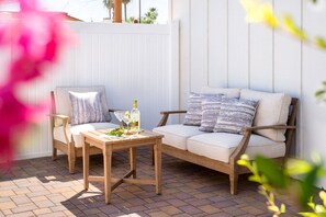 A patio with a wooden table, two chairs, and a cushioned sofa. - Modern 2BR Casita | Roosevelt Row & Downtown (Phoenix)