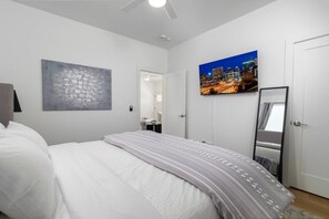 A bedroom with a bed, a cityscape painting, a mirror, and a door. - Modern 2BR Casita | Roosevelt Row & Downtown (Phoenix)